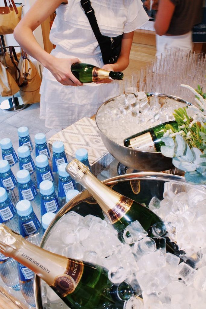Elegant event setup with champagne bottles in ice buckets, water, and guests.
