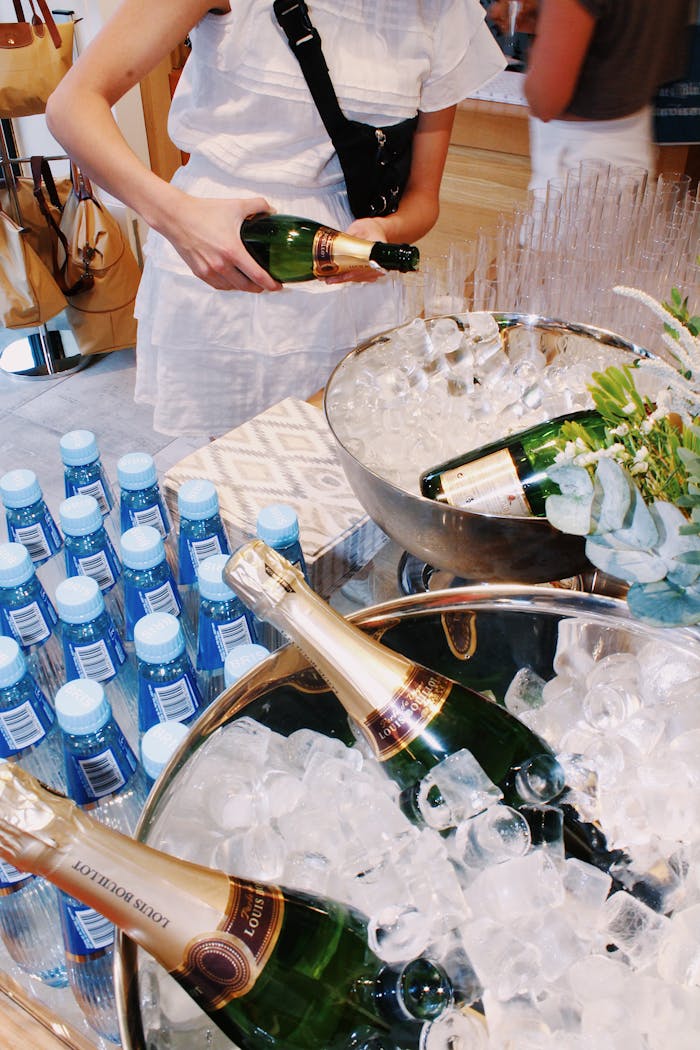 Elegant event setup with champagne bottles in ice buckets, water, and guests.